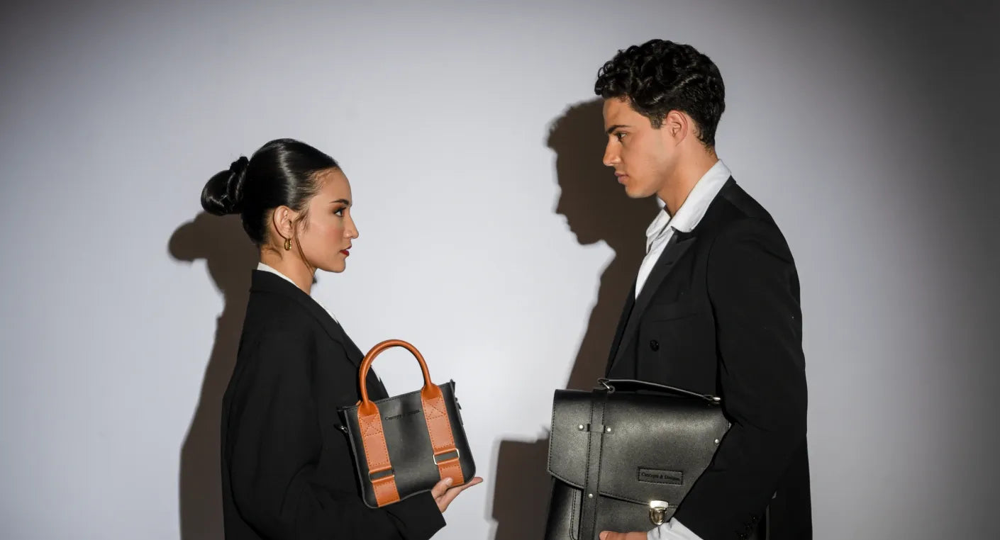 Two people holding handbags against a plain background