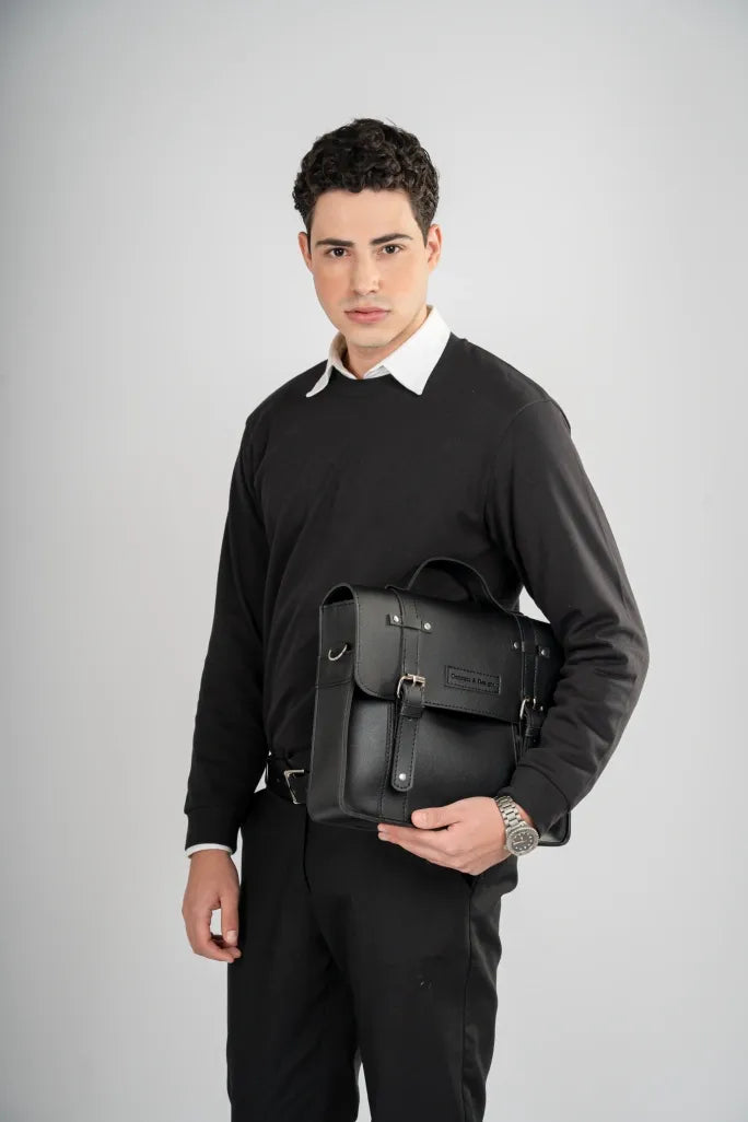 Man holding a black leather backpack against a gray background