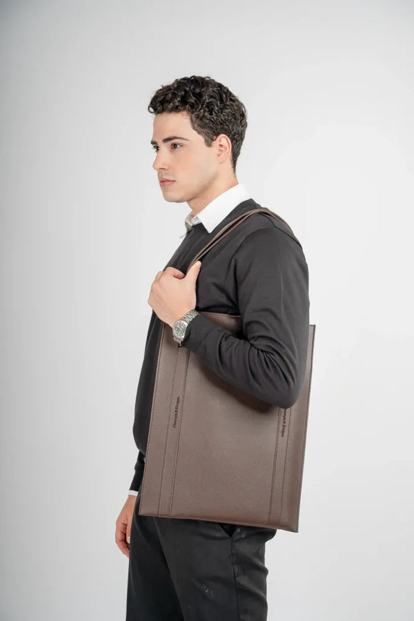 Man holding a brown leather bag against a white background