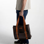 Man holding a brown leather bag against a white background
#color_espresso