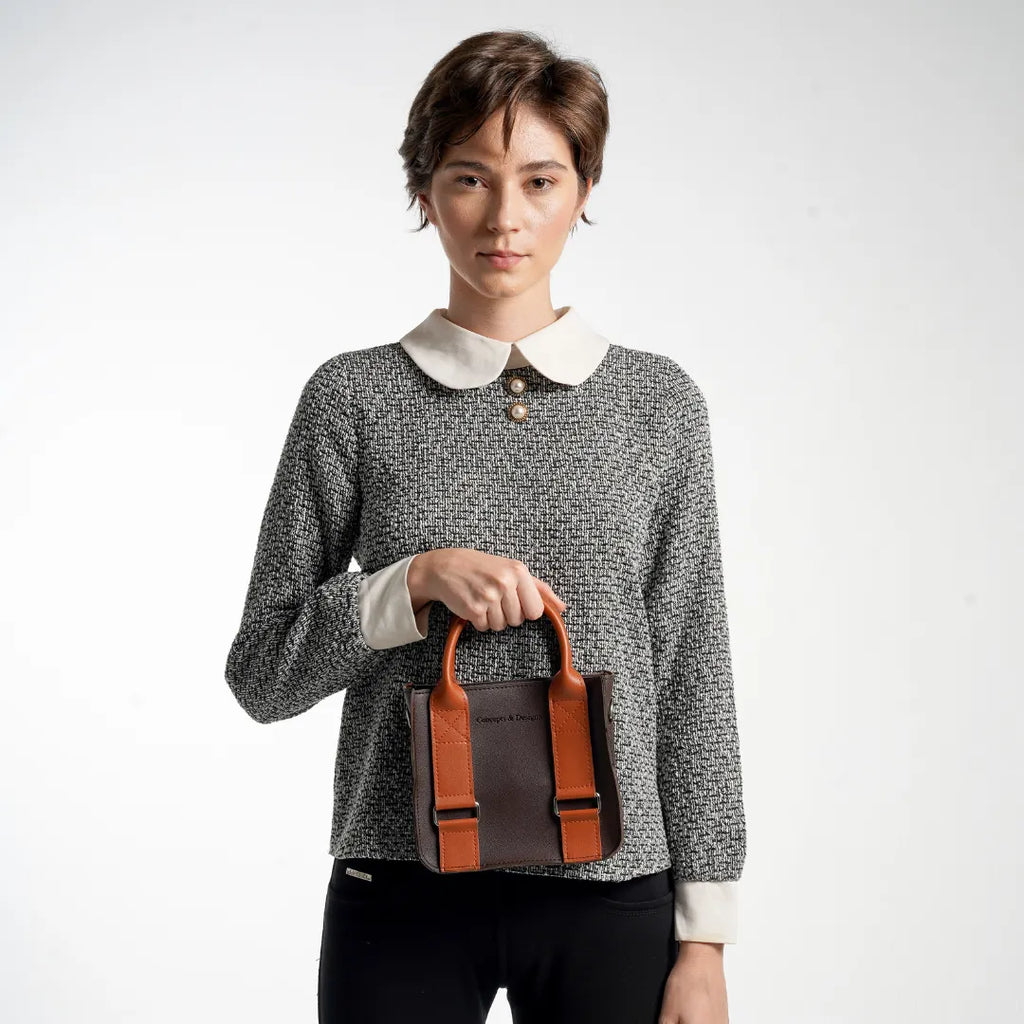 Woman holding a brown leather bag against a white background
#color_espresso
