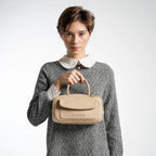 Woman holding a beige handbag against a white background
#color_light beige