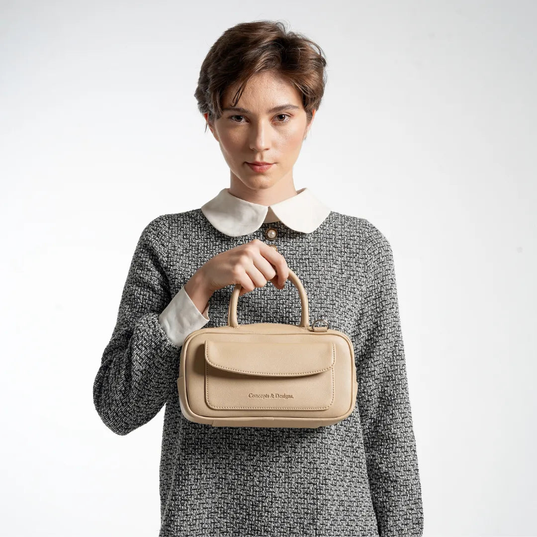 Woman holding a beige handbag against a white background
#color_light beige