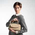 Woman holding a beige handbag against a white background
#color_light beige
