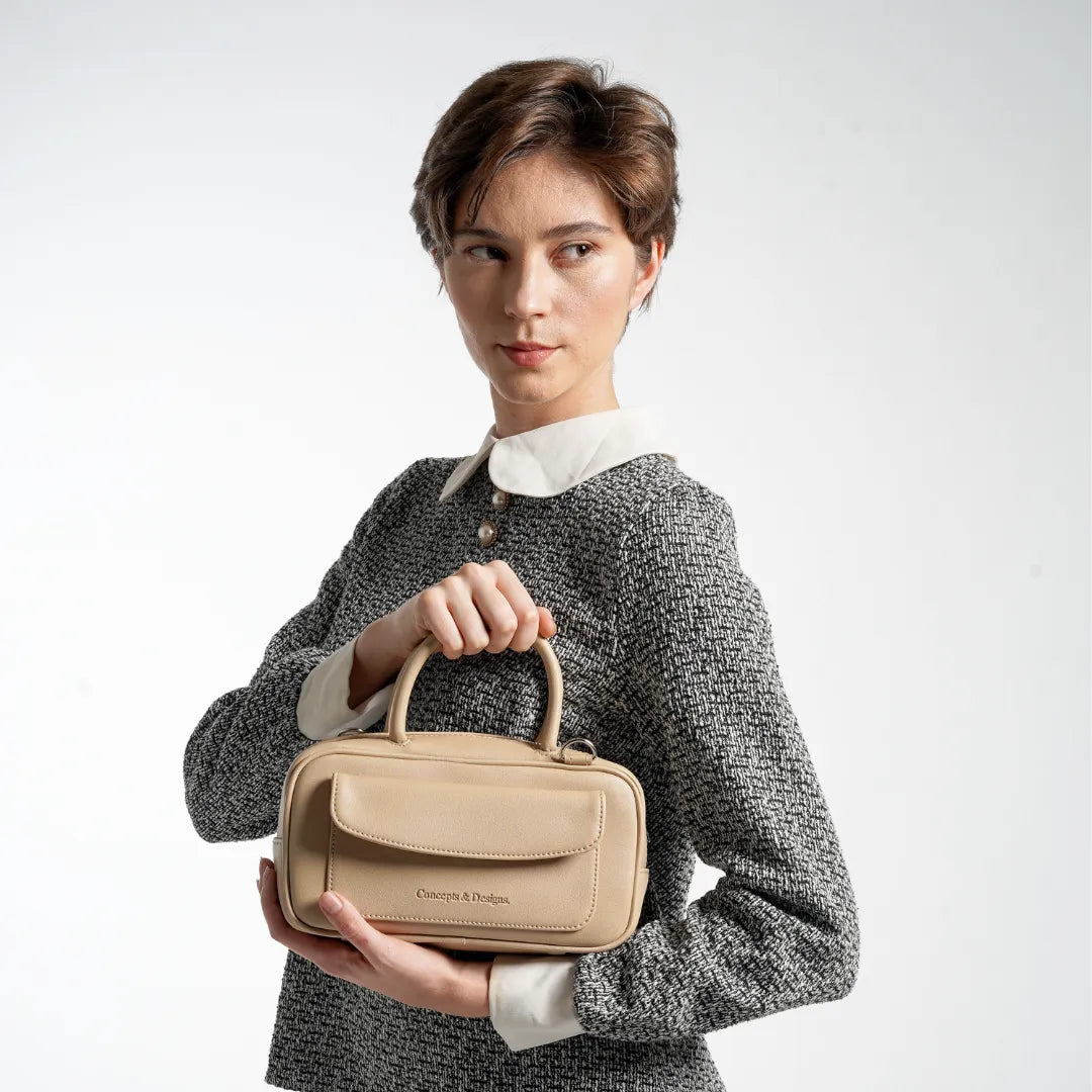 Woman holding a beige handbag against a white background
#color_light beige
