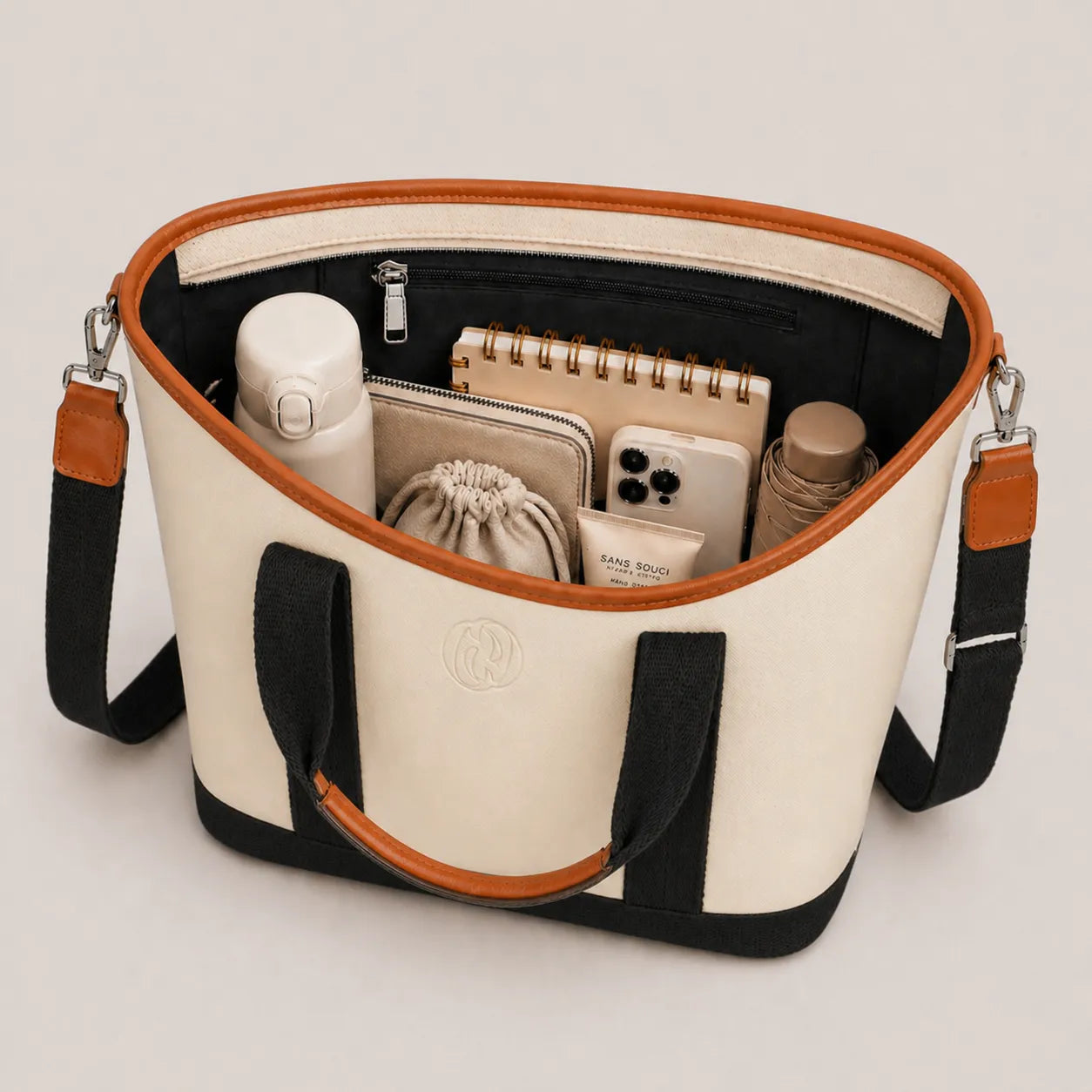 Open tote bag with black and white design, containing various items on a light gray background
#color_malibu