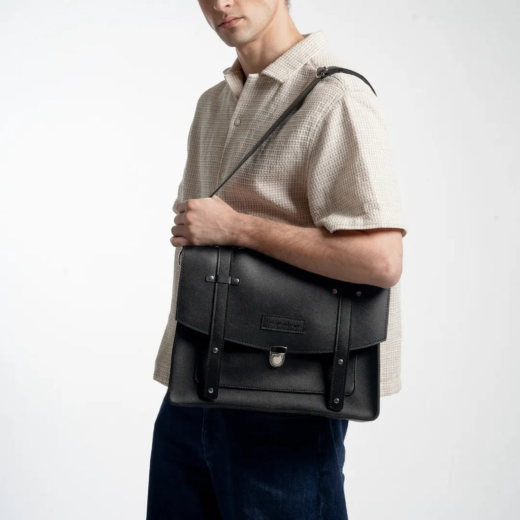 Man holding a black leather briefcase against a white background
#color_midnight