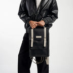 Man holding a black backpack with beige accents on a white background
#color_charcoal