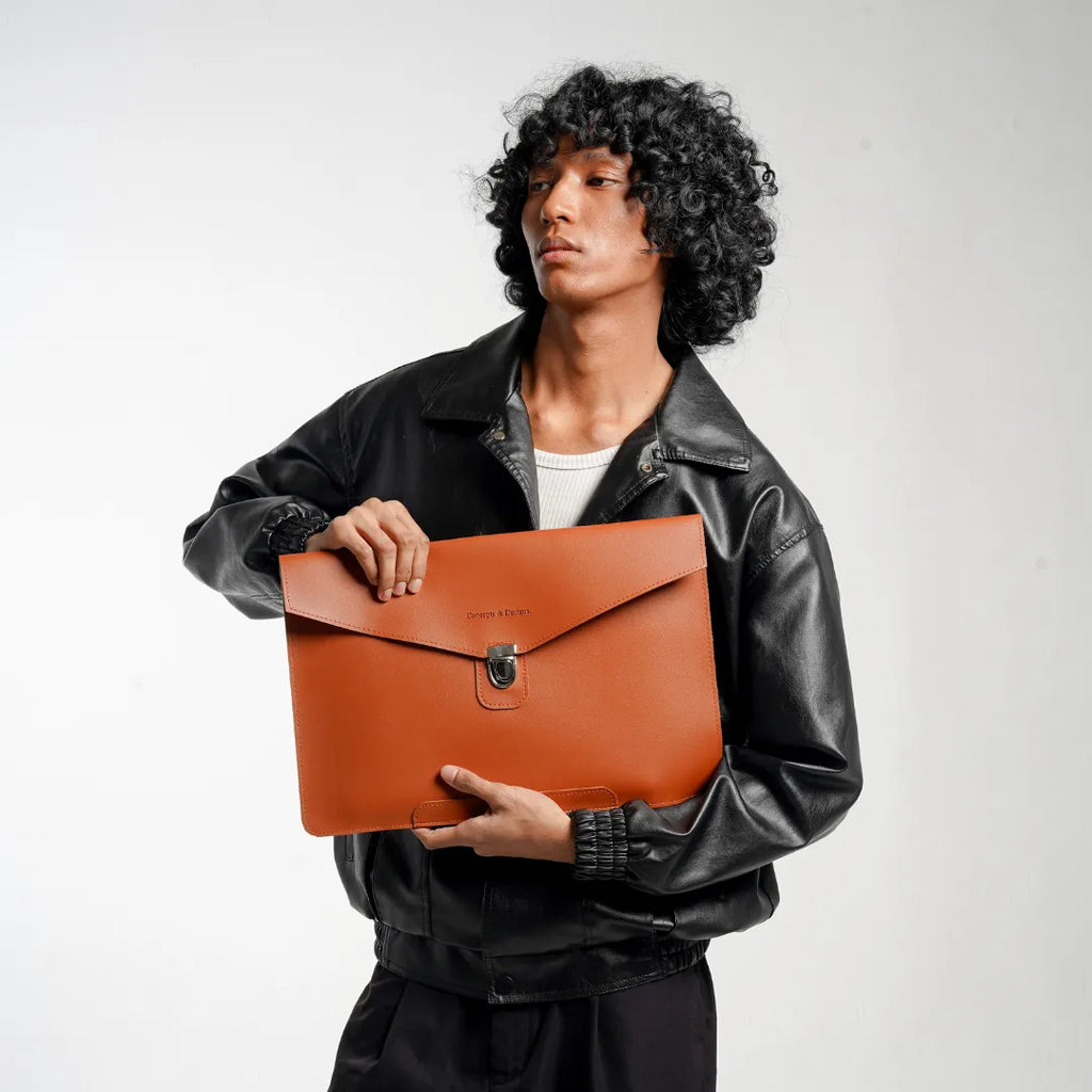 Person holding a brown leather clutch bag against a plain background
#color_chestnut