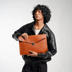 Person holding a brown leather clutch bag against a plain background
#color_chestnut