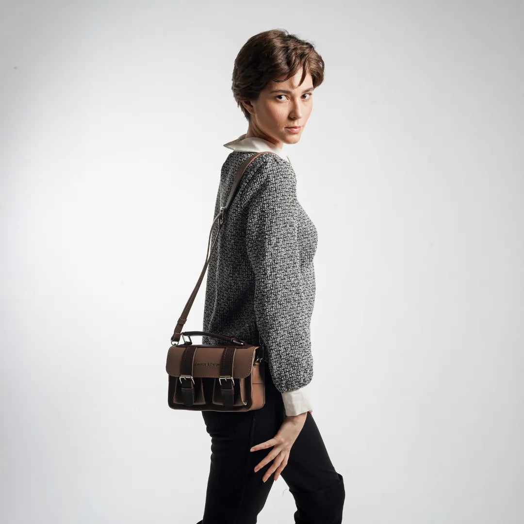 Person holding a brown leather tool bag against a white background
#color_umber