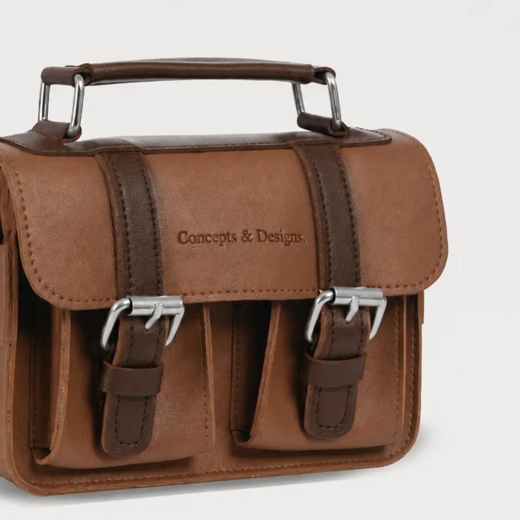 Brown leather satchel bag with metal buckles on a light gray background
#color_umber