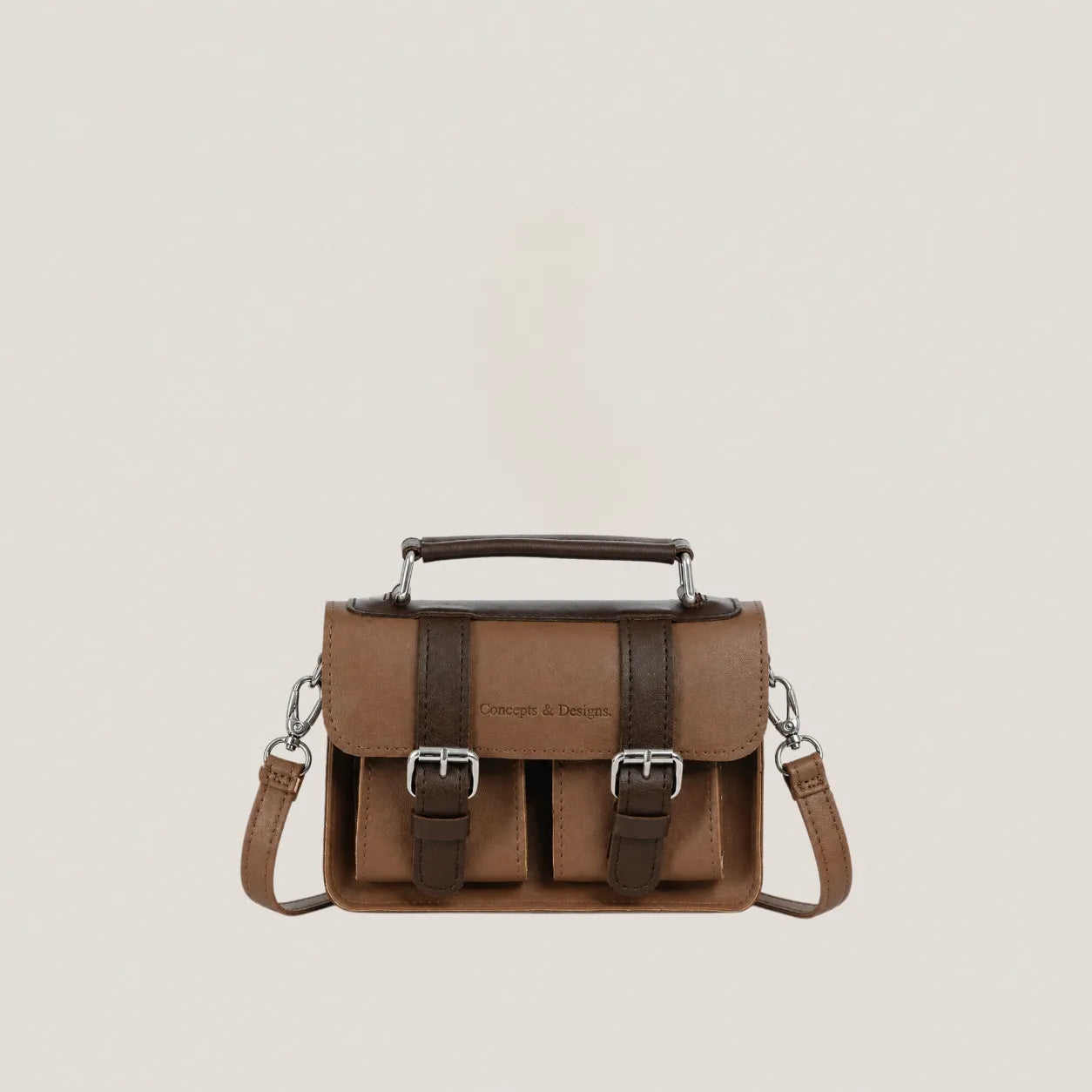 Brown leather satchel bag with silver buckles on a beige background
#color_umber