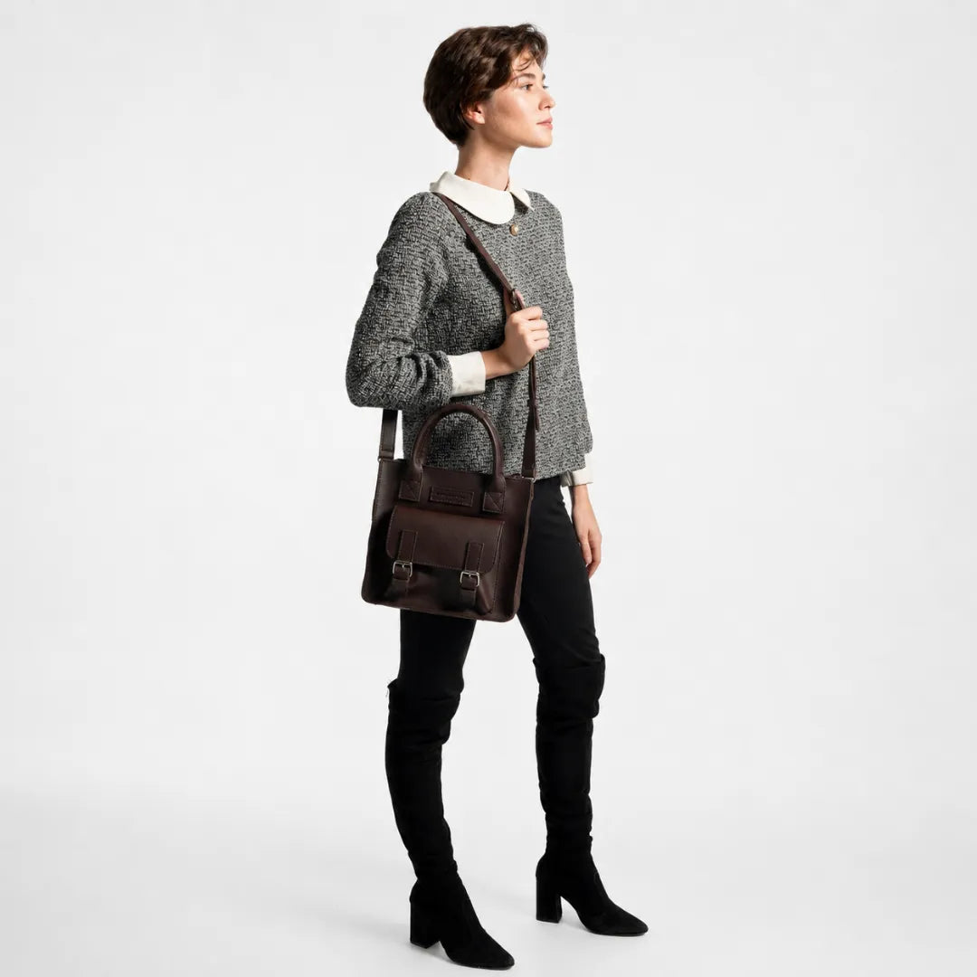 Woman holding a brown leather bag against a white background
#color_dark brown