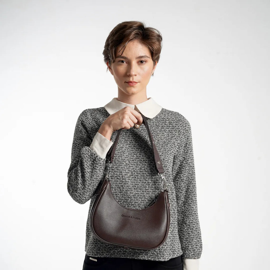 Person wearing a gray sweater with a white collar holding a brown leather bag on a white background
#color_brown