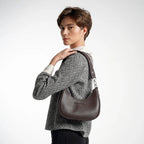 Person wearing a patterned sweater and carrying a brown leather handbag on a white background
#color_brown