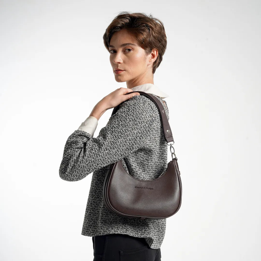Person wearing a patterned sweater and carrying a brown leather handbag on a white background
#color_brown